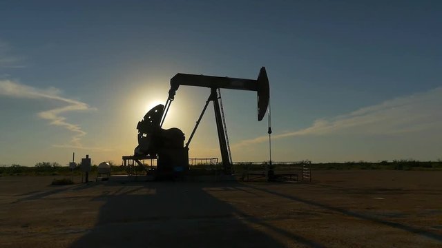 Industrial jack pump working on oil field at summer sunset