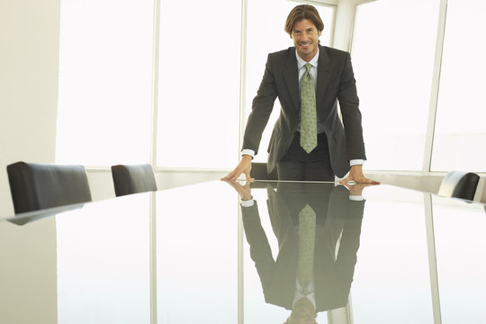 Portrait Of Happy Businessman Leaning His Hands On Conference Table