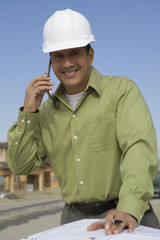 Portrait of a happy male architect on call at construction site