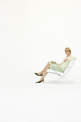 Portrait of confident businesswoman sitting on modern chair isolated on white background
