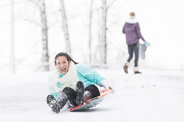 Two young girls sledding down hill in ice and snow