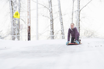 Young girl playing on a snow sled