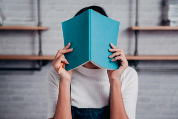 Asian women are covered with blue book.Focus on book