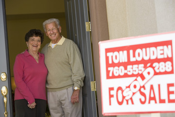 Portrait of a happy senior couple standing at doorway of their new house