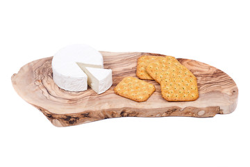 Soft ripened goat milk brie cheese with vegetable crackers on olive wood cutting board isolated on white background