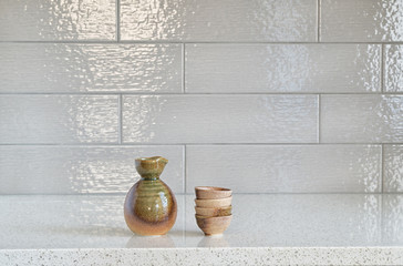 Set of sake cups and container on granite countertop against cer