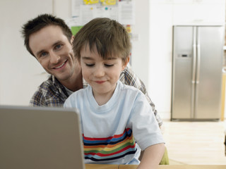 Portrait of happy father with son using laptop at home