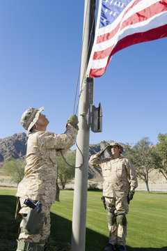 Soldiers Raising United States Flag Against The Sky