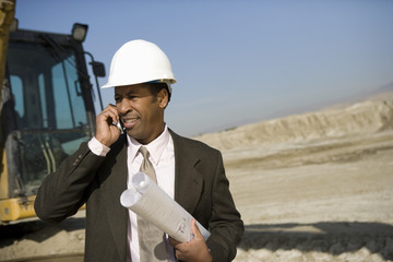 African American architect using cellphone at construction site