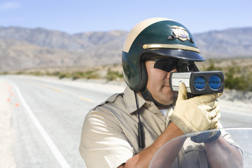 Mature traffic officer monitoring speed through radar gun