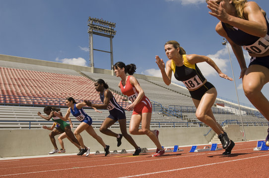 Group of runners taking off from starting block in race