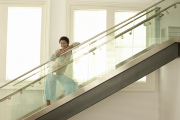 Happy young African American woman standing on modern glass stairs