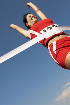 Low angle view of a female runner winning race against the blue sky