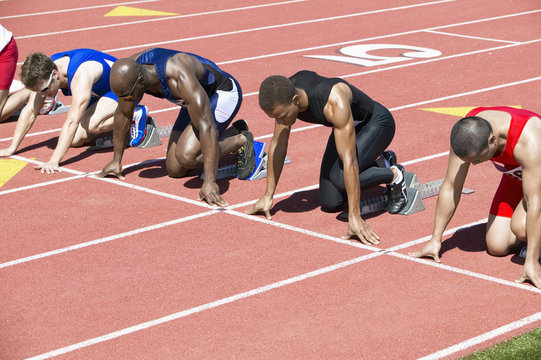 Group of multiethnic male athletics waiting at starting blocks