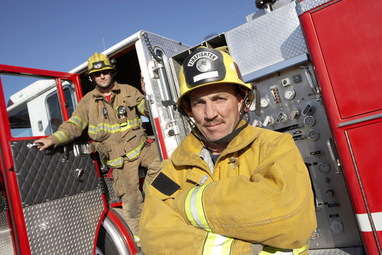 Portrait of a confident firefighter with coworker in the background