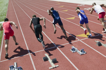 Fototapeta premium Rear view of multiethnic runners starting race on racetrack
