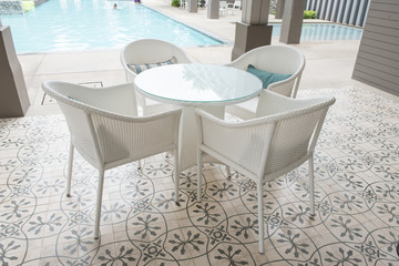 chairs and tables front of a swimming pool.