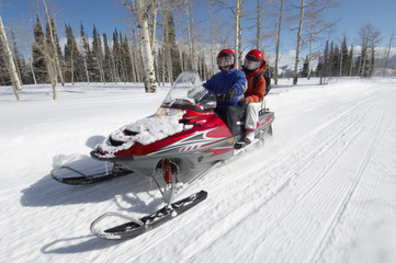 Couple driving snowmobile on snow covered track