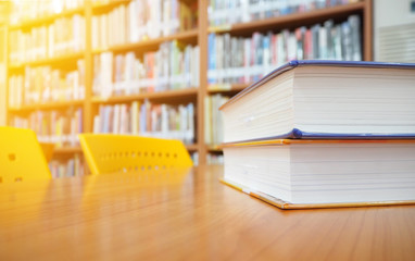 Book stack on wood desk in the library room and morning light, education concept