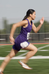 Blurred motion of Asian female athlete running on racetrack