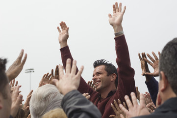 Low angle view of celebrity raising hands for crowd against clear sky