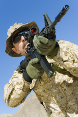 Low angle view of soldier aiming through gunsight against clear blue sky