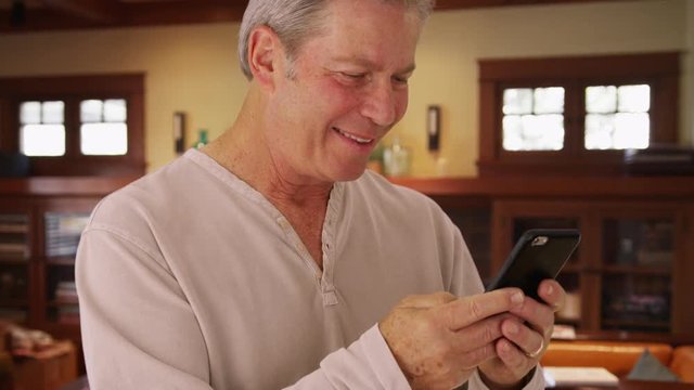 Mature middle aged male reading text message on cellphone device
