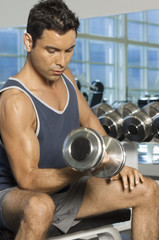 Fototapeta na wymiar Healthy man lifting weights at a gym