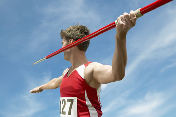 Male athlete about to throw javelin against the sky