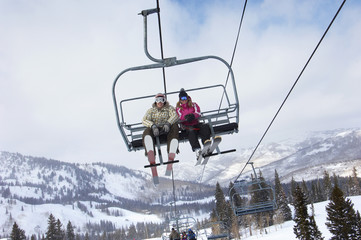 Fototapeta na wymiar Low angle view of a couple in skies sitting on ski lift 