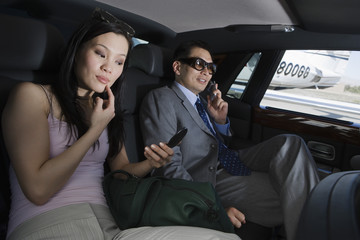 Businessman on a call while businesswoman looking herself in mirror