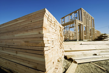 New home under construction with stacked of wooden planks in foreground