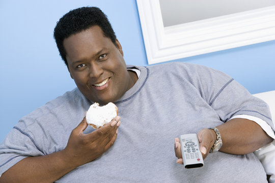 Portrait Of An African American Obese Man Holding Donut