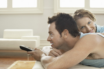 Portrait of young woman with man holding remote control at home