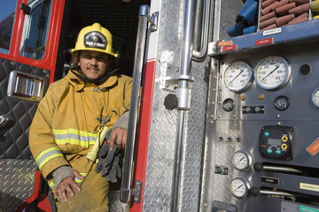 Portrait of a mature fire fighter sitting at fire brigade's door