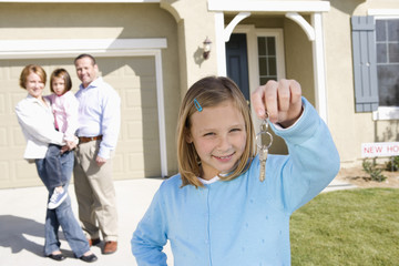 Obraz premium Portrait of happy girl with family holding key in front of new house