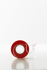Roll of red tape in dispenser isolated over white background