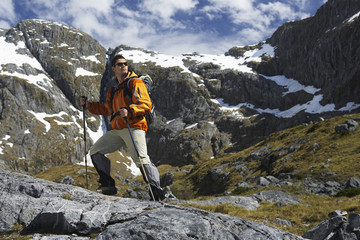 Full length side view of a male hiker with walking sticks in mountains