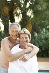 Portrait of middle aged man embracing woman from behind outdoors