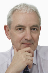 Closeup portrait of confident middle aged businessman with hand on chin over white background
