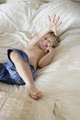 Obraz na płótnie Canvas Cheerful boy lying in bed at home