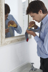 Middle aged business man cleaning stain from tie in front of mirror