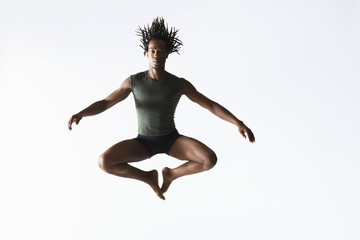 Full length of African American male ballet dancer jumping isolated on white background