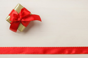 Small golden box with gift tied red bow