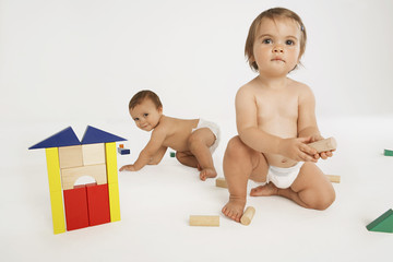 Baby girl and baby boy playing with building blocks isolated on white background