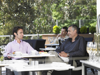 Happy businessmen conversing at outdoor cafe