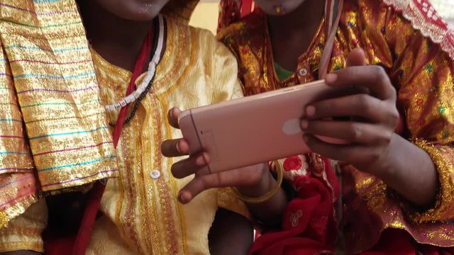 Young Girls on cell phone mobile dressed as Hindu goddess with make-up and traditional clothing at the Pushkar Mela festival in Rajasthan, India 