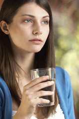 Closeup of beautiful young woman holding glass of water