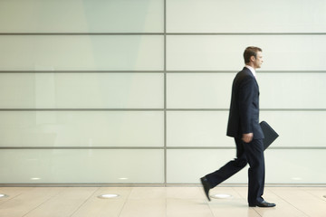 Fototapeta na wymiar Side view of young businessman walking in passage of office
