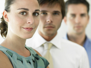 Closeup portrait of beautiful businesswoman with male colleagues in background